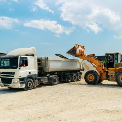 pexels-photo-3089685-3089685 Excavator loading materials into a heavy-duty truck at a sunny construction site.